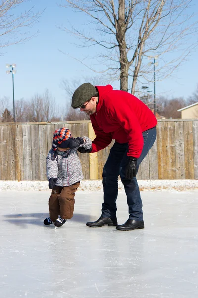 Отец учит сына кататься на коньках — стоковое фото