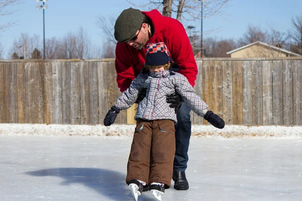 Father teaching son how to ice skate — Stok fotoğraf