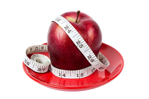 Dieting concept Red apple with measuring tape on red plate — Stock Photo, Image