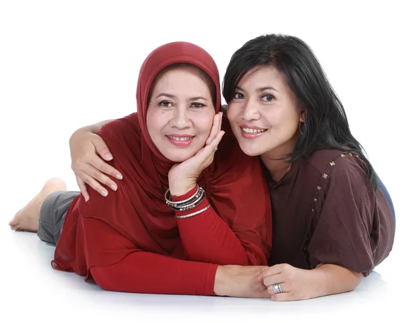 Mujer musulmana con su hija acostada aislada sobre fondo blanco — Foto de Stock