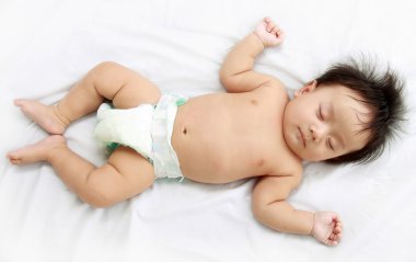 Baby laying in the bed. clipart