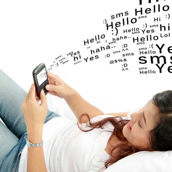 Frau telefoniert im Bett liegend per SMS — Stockfoto