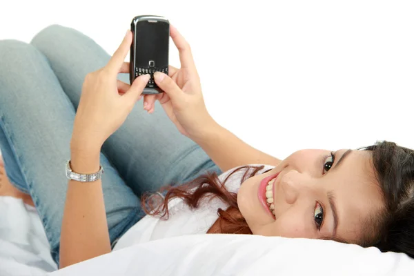 Kvinna textning på telefon liggande på sängen — Stockfoto