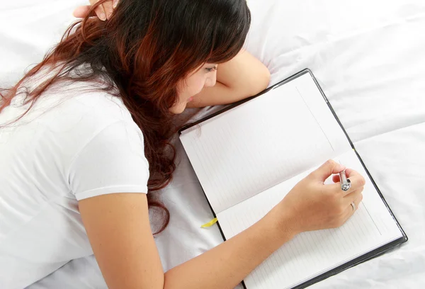 Dívka psaní knihy na postel — Stock fotografie