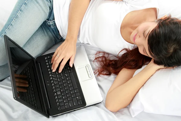 Девушка лежит в постели с ноутбуком — стоковое фото