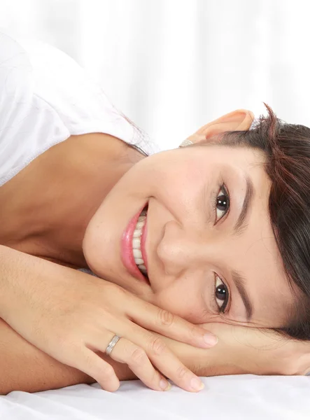 Kobieta uśmiechając się leżąc na łóżku — Zdjęcie stockowe