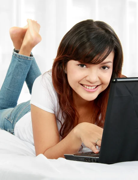 Femme avec ordinateur portable sur le lit — Photo