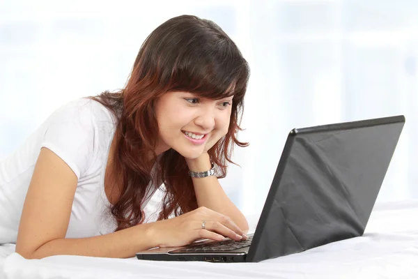 Woman with laptop on bed Stock Image