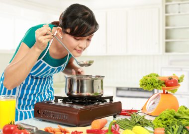 Woman is tasting her cooking clipart