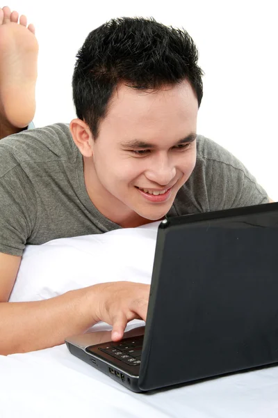 Uomo che utilizza computer portatile su un letto — Foto Stock