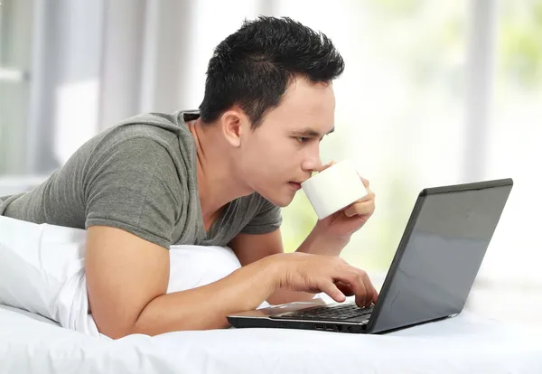 남자는 침대에 누워 노트북 컴퓨터를 사용 하 여 — 스톡 사진