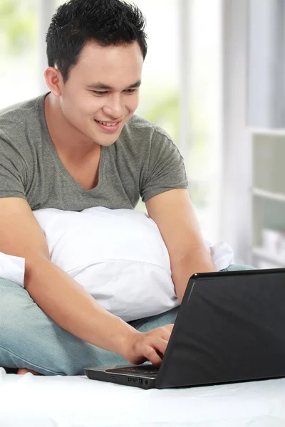 Mann benutzt Laptop auf einem Bett — Stockfoto