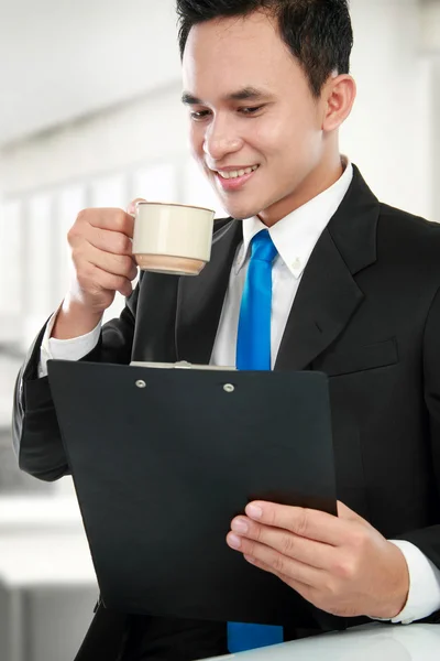 Executive reading a report while drinking — Stock Photo, Image