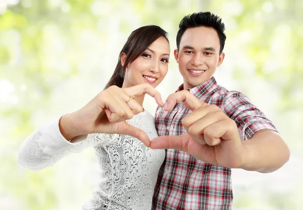 Молодая пара показывает сердце с пальцами — стоковое фото