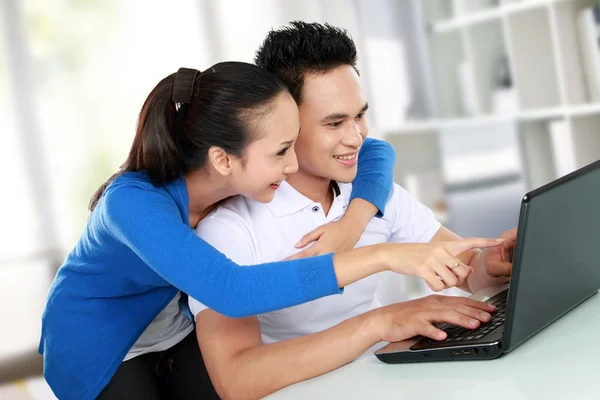 Casal sorrindo usando um laptop — Fotografia de Stock