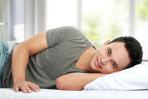 Mann liegt lächelnd im Bett — Stockfoto