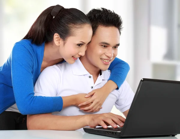 Smiling couple using a laptop — Stok fotoğraf