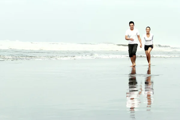 在海滩上奔跑的情侣 — 图库照片