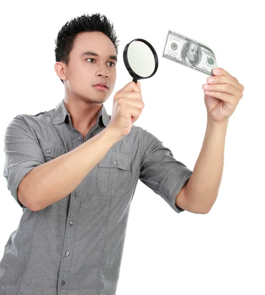 Человек смотрит на долларовую купюру через увеличительное стекло — стоковое фото