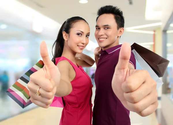 Casal com sacos de compras mostrando polegar para cima — Fotografia de Stock