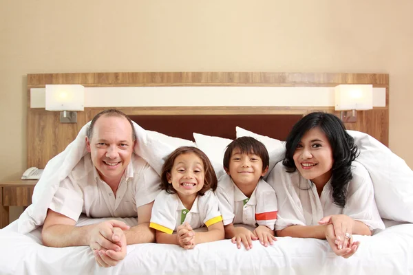Счастливая семья на белой кровати — стоковое фото
