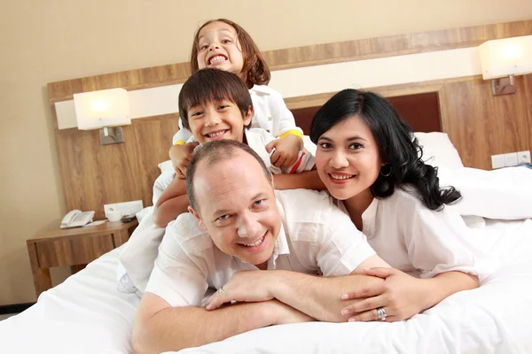 Счастливая семья на белой кровати — стоковое фото