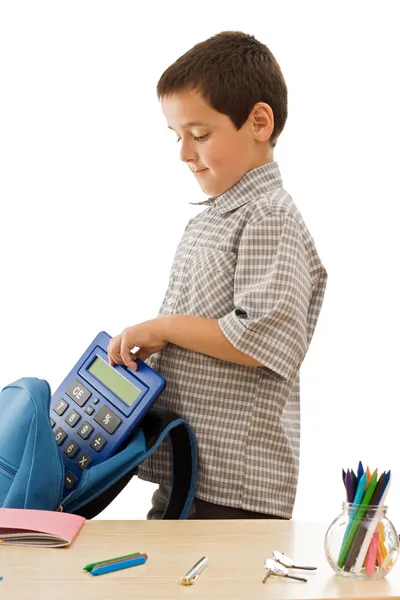 Schoolboy colocando uma calculadora no saco escolar — Fotografia de Stock