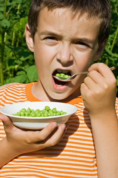 Junge isst Erbsen — Stockfoto