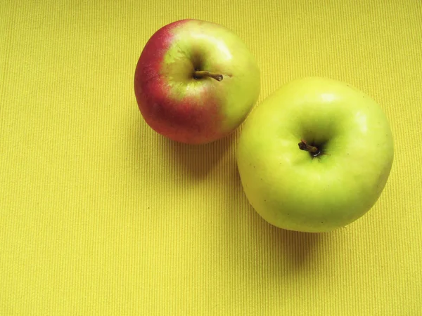 Dvě jablka na žlutém podkladu — Stock fotografie