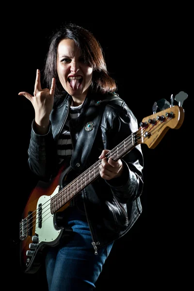 Mujer de rock con guitarra eléctrica bajo haciendo la señal de los cuernos con la lengua fuera — Foto de Stock