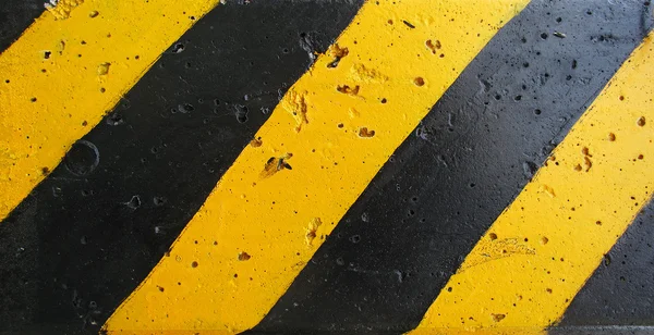 Velhas tiras pretas e amarelas na parede — Fotografia de Stock