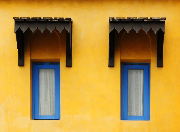 青い窓と黄色のグランジ壁に木製の屋根 — ストック写真
