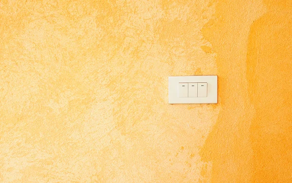 Vit strömbrytare på en orange grunge vägg — Stockfoto