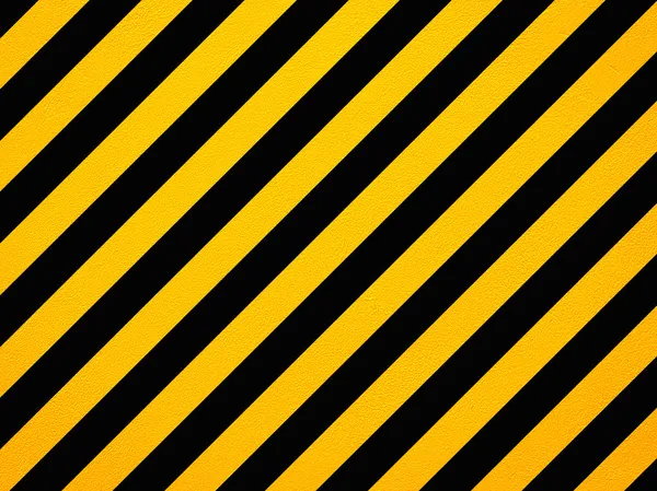 Yellow and black diagonal hazard stripes painted on old brick wa — Stock Photo, Image
