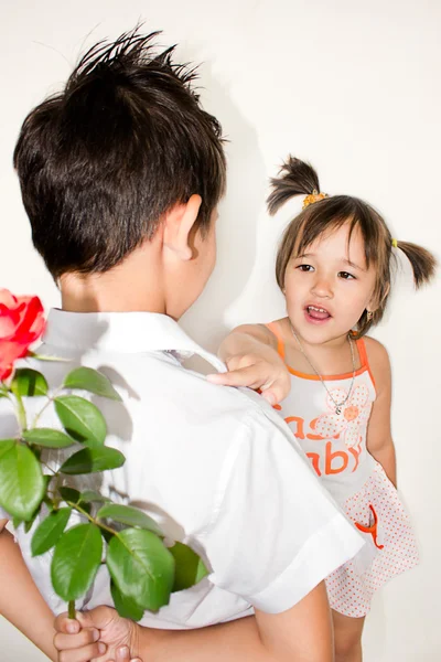 O rapaz dá à menina uma rosa em um fundo branco — Fotografia de Stock