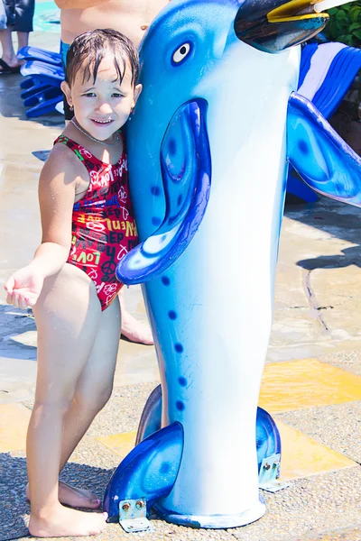 Ein kleines Mädchen in der Nähe des Pools mit einem Delfin — Stockfoto