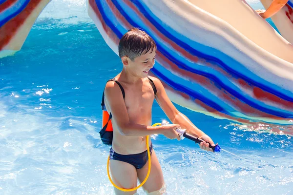 Ένα μικρό αγόρι που παίζουν στην πισίνα με ένα πιστόλι νερού — Φωτογραφία Αρχείου