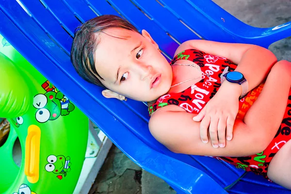 Kleines Mädchen liegt auf einer Liege am Pool — Stockfoto