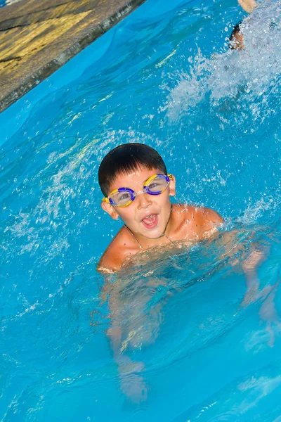 Ein kleiner Junge schwimmt im Wasser lizenzfreie Stockbilder