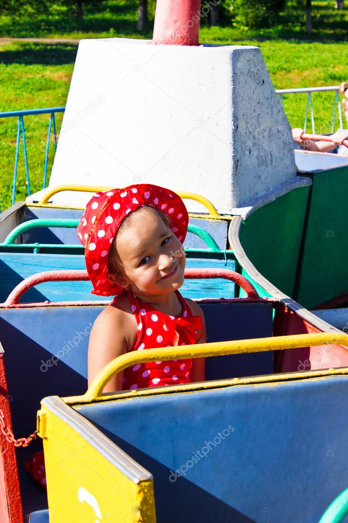 A little girl riding on a children's train