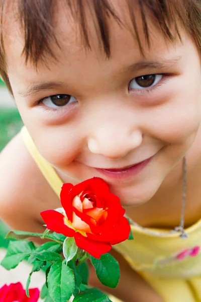 Doce, doce menina respira fragrância de uma rosa — Fotografia de Stock