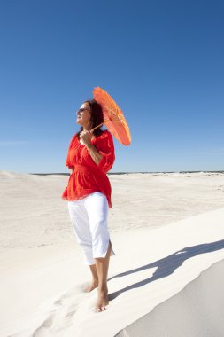 Lonely but happy woman on desert sand dune clipart