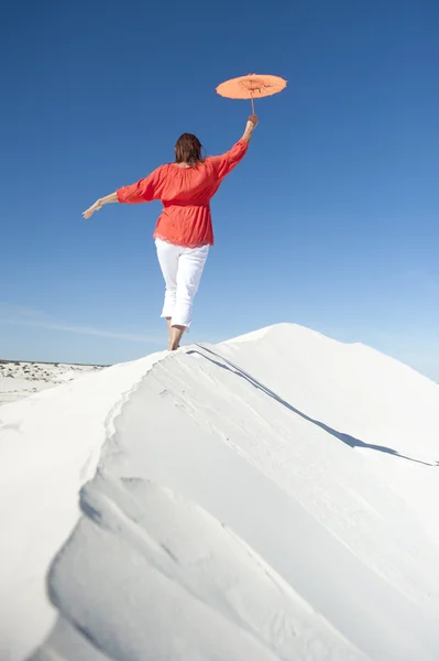 Женщина балансирует на краю песчаной дюны пустыни — стоковое фото