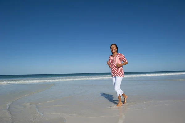 Зрелая веселая здоровая женщина, тренирующаяся на пляже — стоковое фото