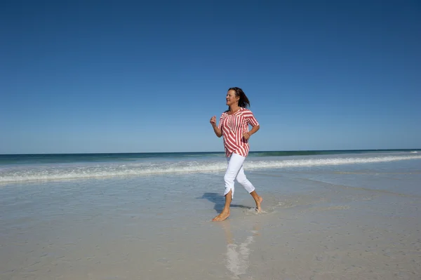 Зрелая веселая здоровая женщина, тренирующаяся на пляже — стоковое фото