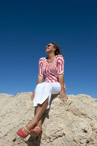 Wysoki obcas kobieta na białym tle siedzi na skale — Zdjęcie stockowe
