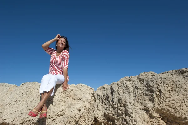 Wysoki obcas kobieta na białym tle siedzi na skale — Zdjęcie stockowe