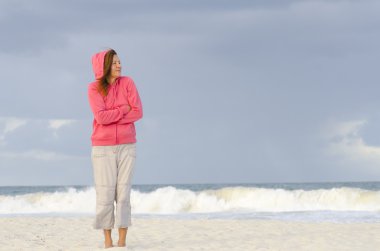 Lonely woman and bad weather at beach clipart