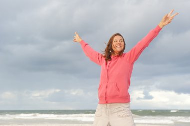 Mature woman positive and happy at ocean clipart