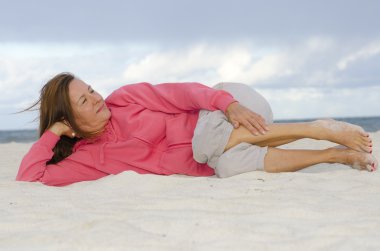 Attractive mature woman relaxed, happy at beach clipart